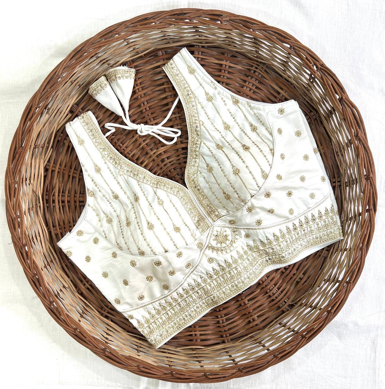 White embroidered blouse with gold details on a woven basket