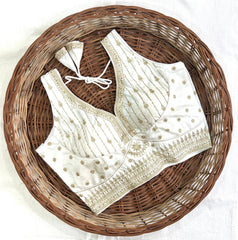 White embroidered blouse with gold details on a woven basket