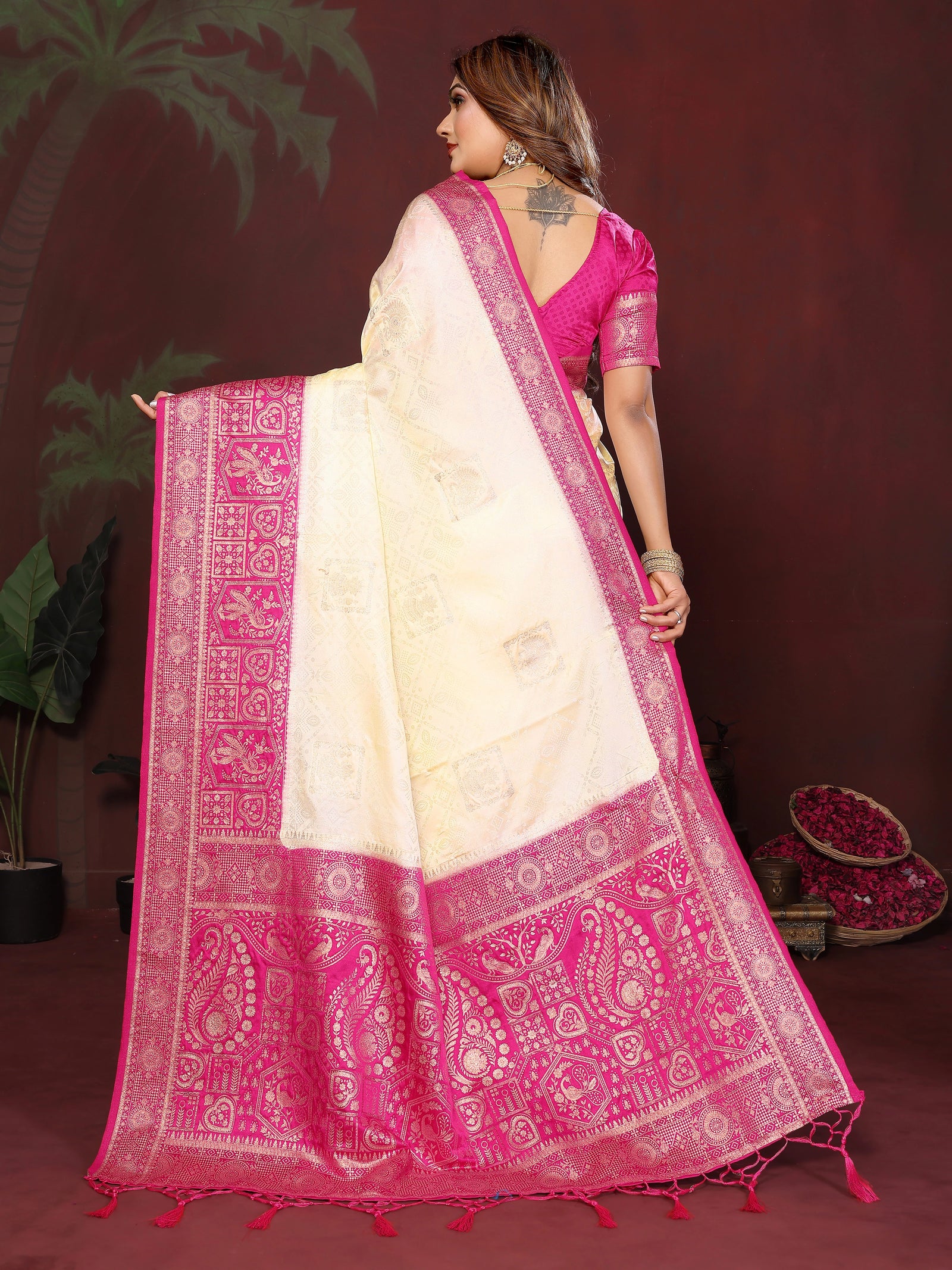Woman wearing a white saree with pink border against a dark background