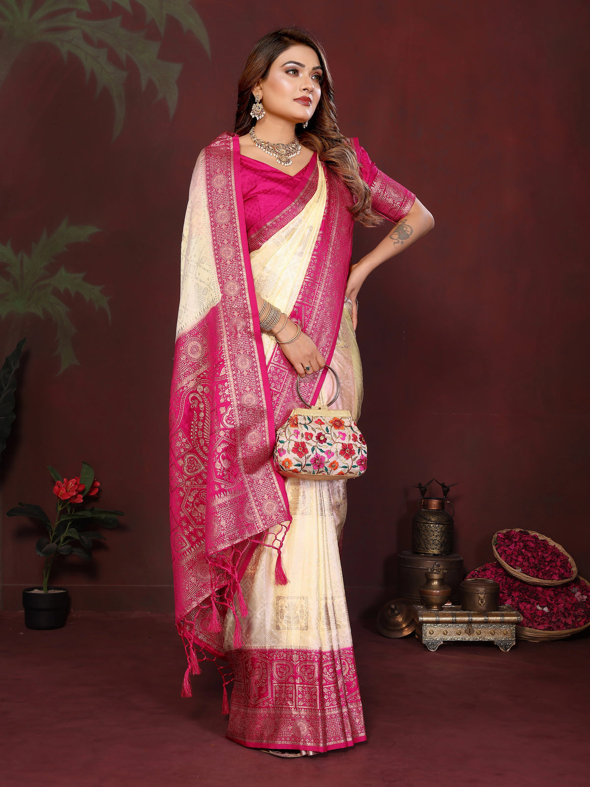 Woman in a pink and white saree with a floral bag on a dark red background