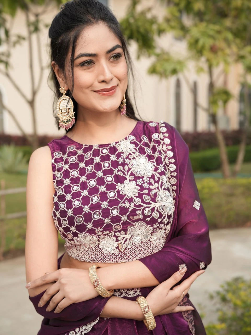 Woman wearing a purple traditional outfit with white embroidery outdoors.