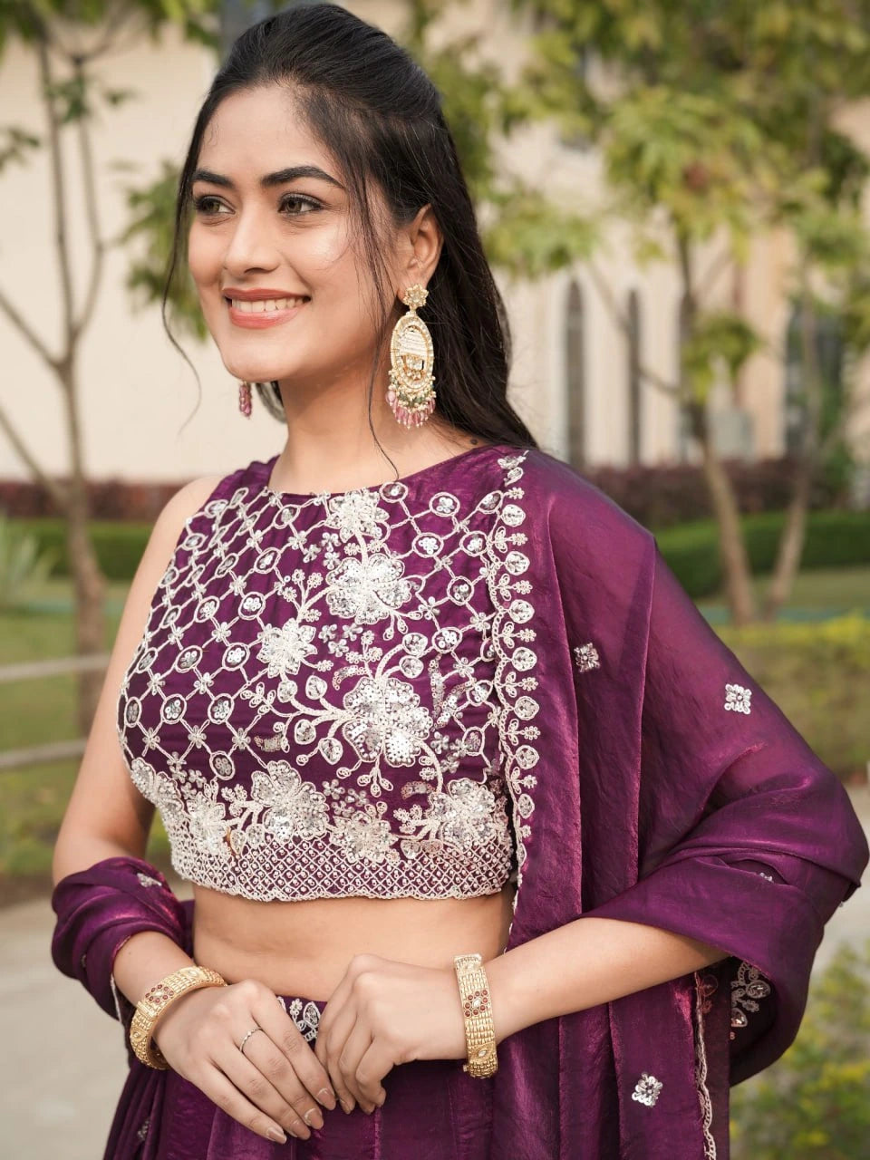 Woman wearing a purple traditional outfit with floral patterns outdoors.