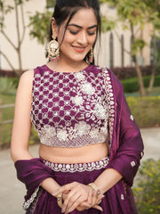 Woman wearing a purple traditional outfit with white embroidery outdoors.