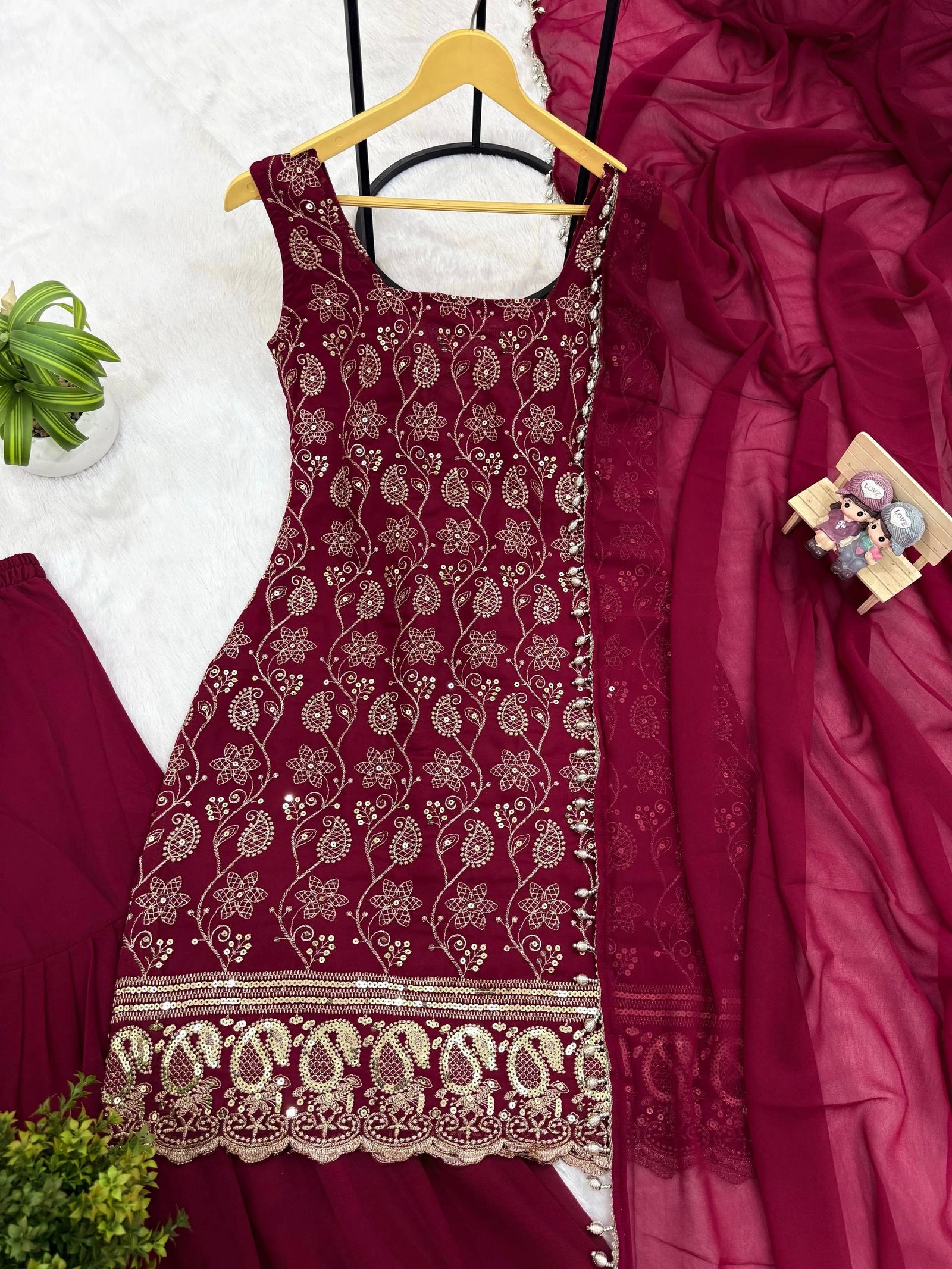 Maroon embroidered dress on a hanger with a close-up of fabric details.