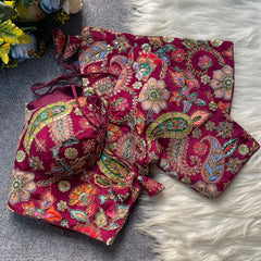 Embroidered pink fabric with floral and paisley patterns on a textured surface.