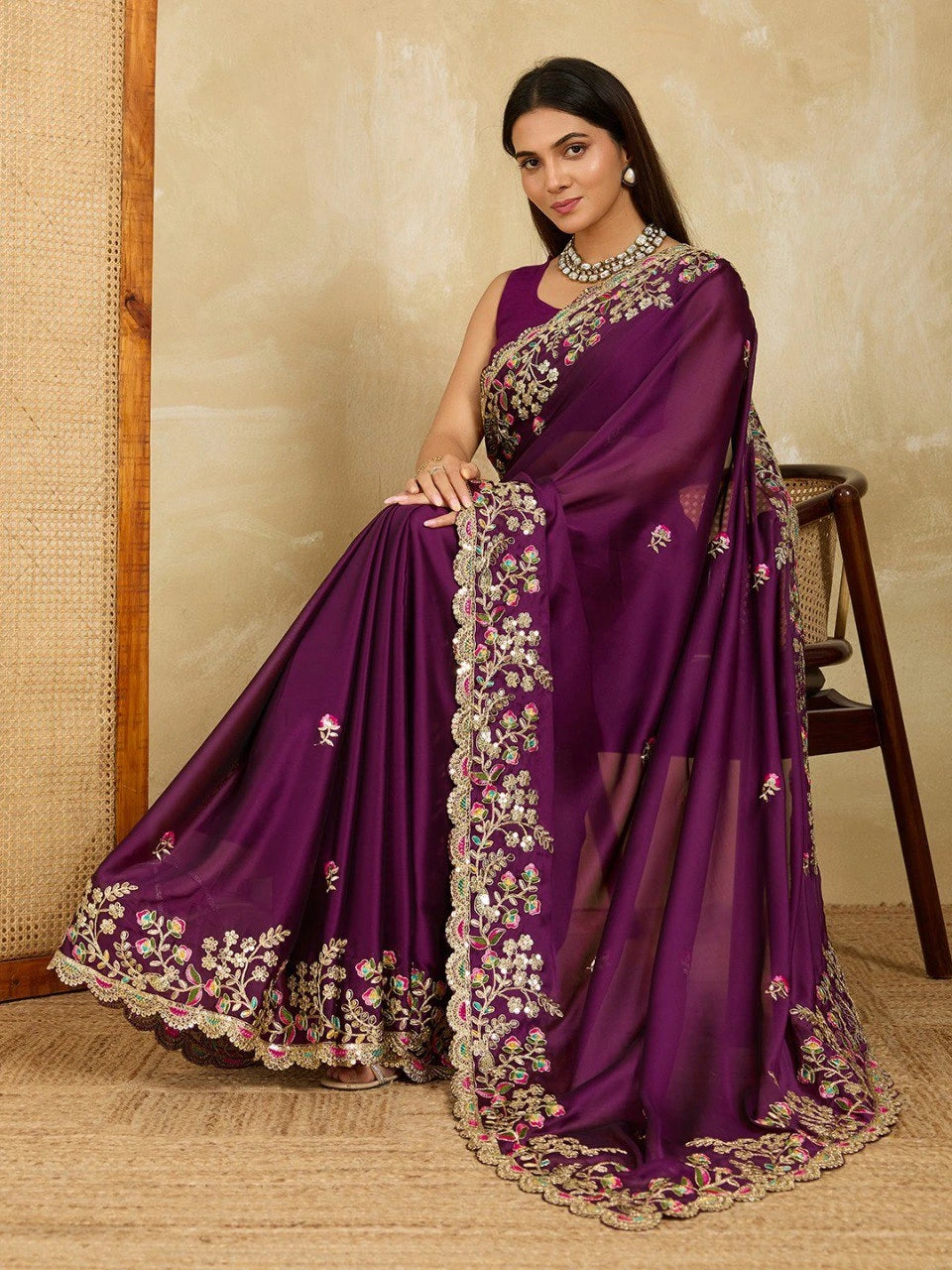 Woman wearing a purple saree with floral patterns on a beige background