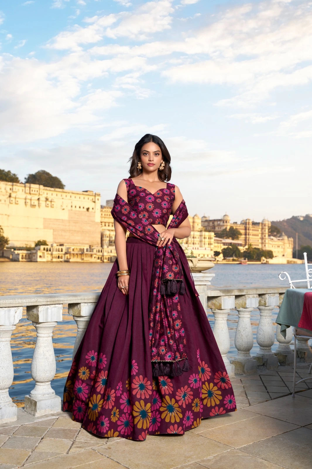 Woman in a purple floral dress standing outdoors with a scenic background