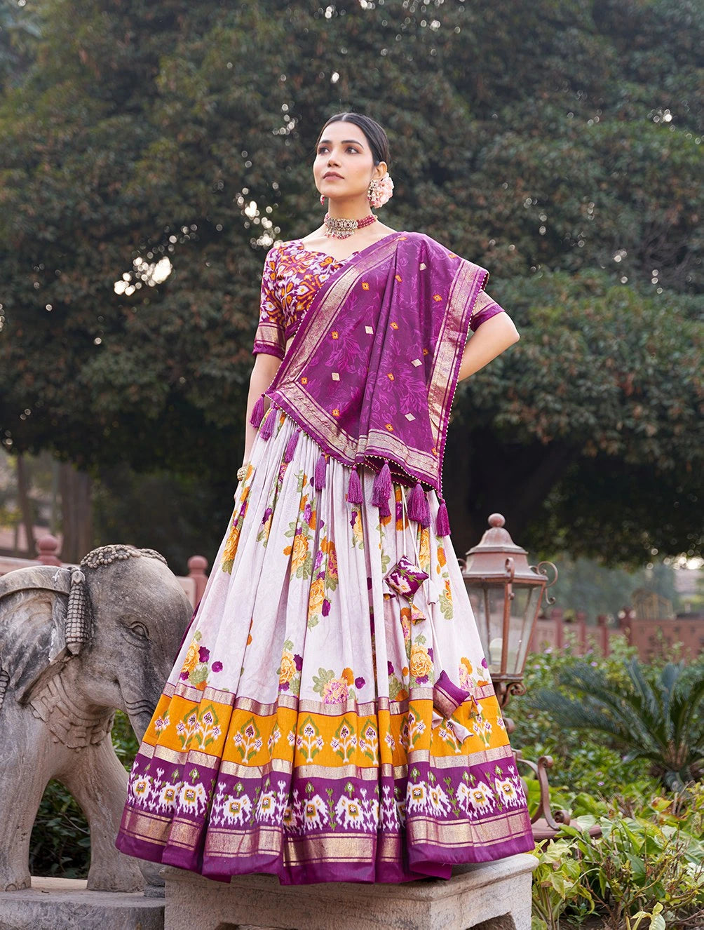 Woman in a traditional outfit with a purple and white saree in an outdoor setting