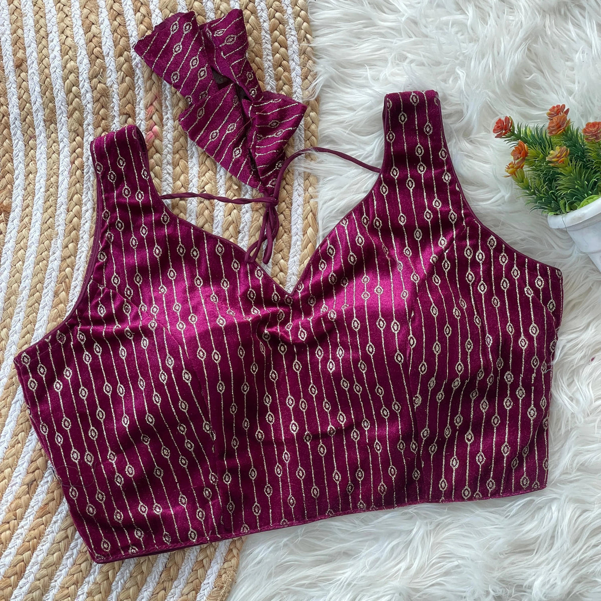 Purple patterned bikini set on a textured surface with a small plant in the corner.