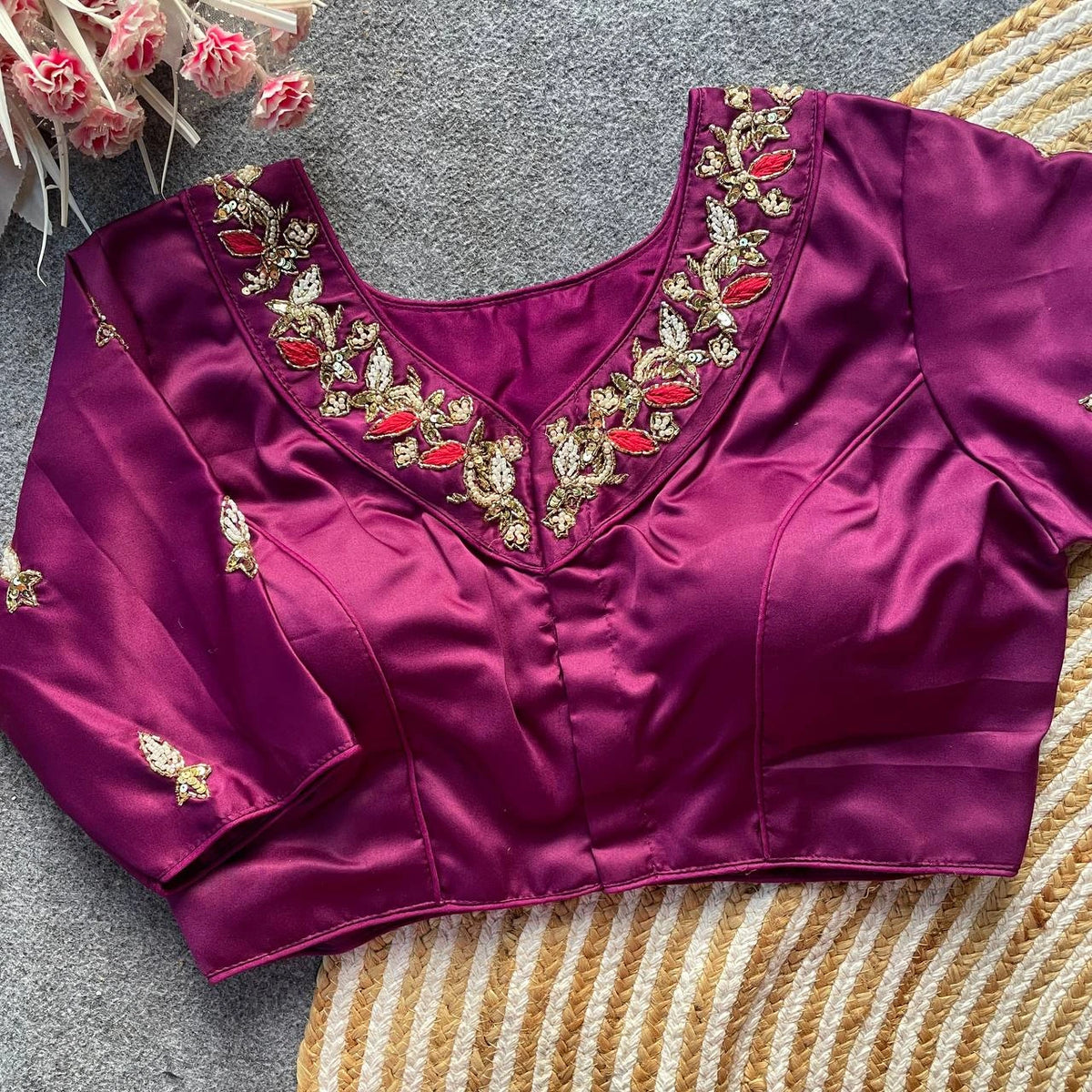 Purple blouse with gold and red embroidery on a textured surface