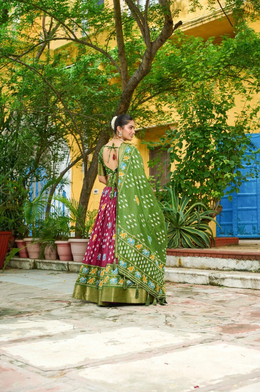 Woman in a green and pink traditional outfit standing in front of a yellow building with blue accents.