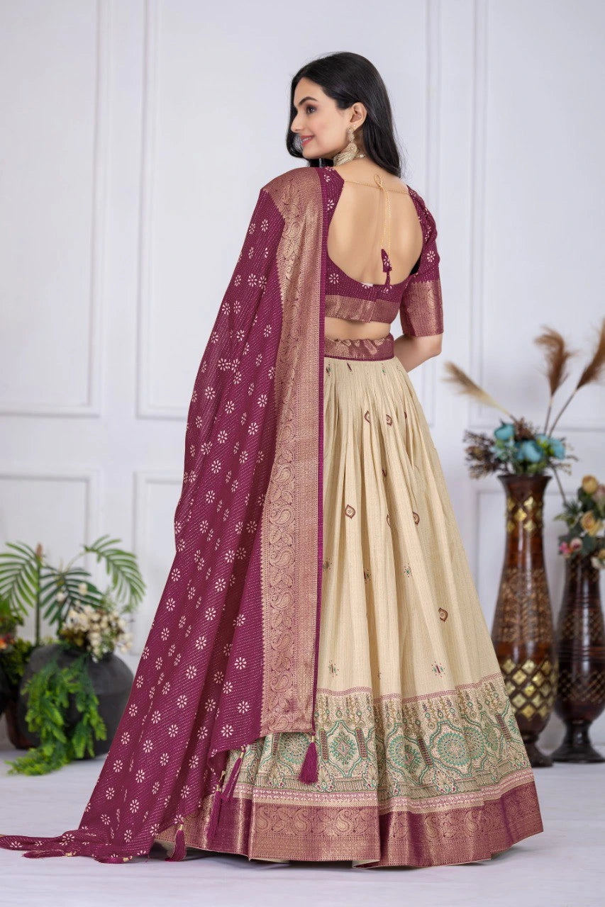 Woman wearing a traditional outfit with a purple dupatta and beige lehenga against a white wall.