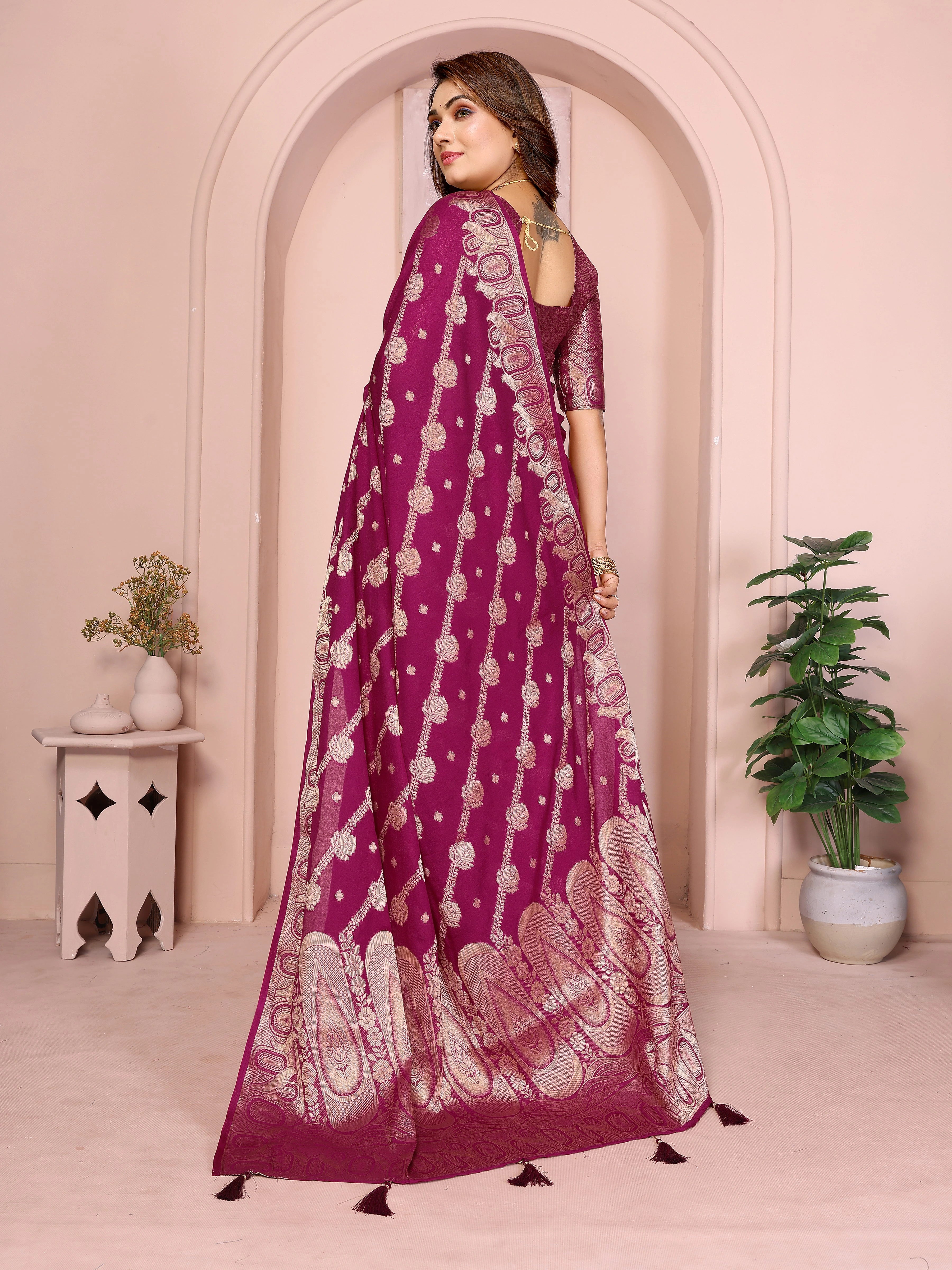 Woman wearing a purple saree with white patterns in a decorated room.