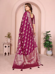 Woman wearing a purple saree with white patterns in a decorated room.