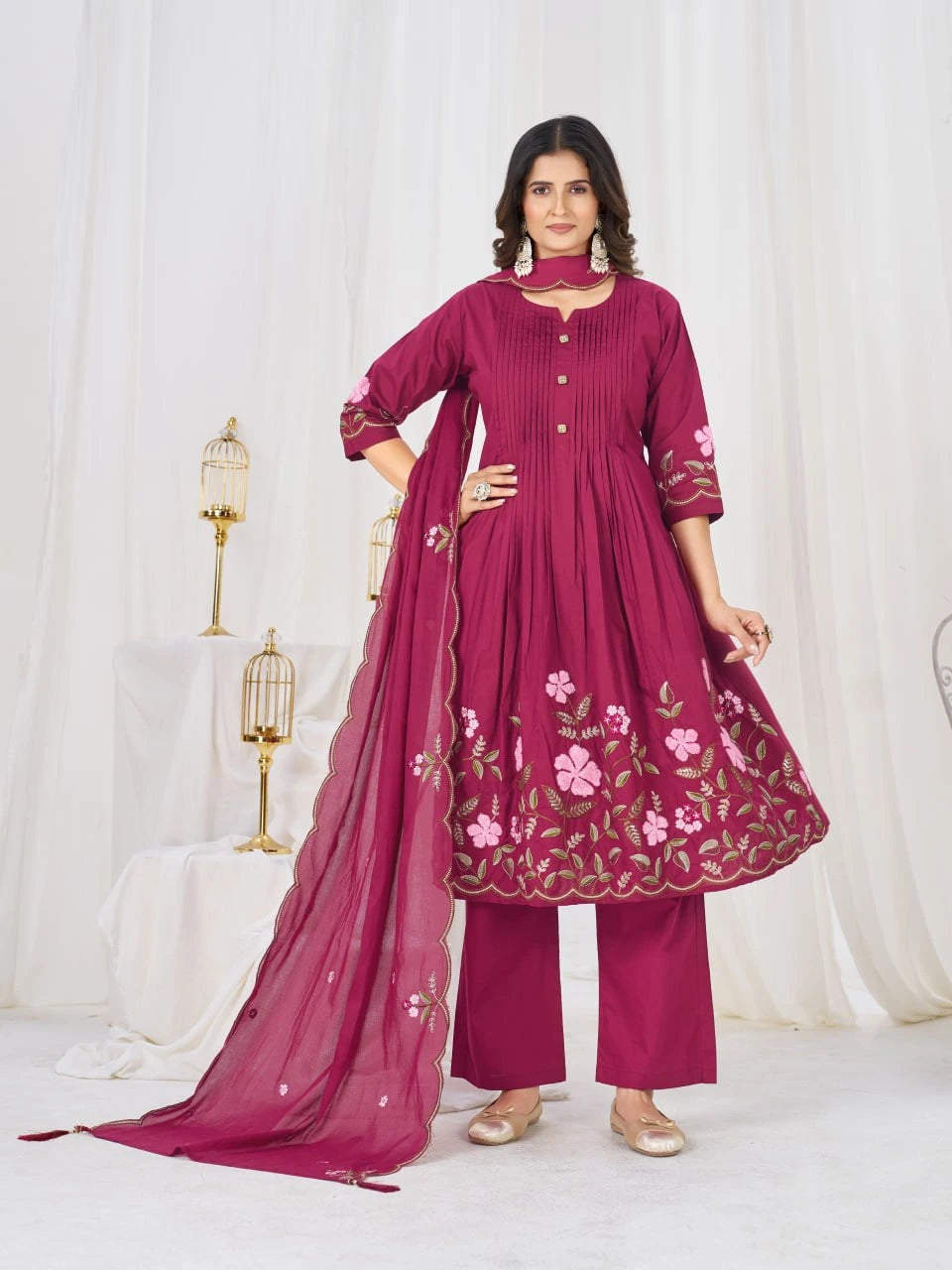 Woman wearing a maroon traditional outfit with floral embroidery on a white background