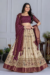 Woman wearing a maroon and beige traditional outfit with a matching dupatta against a neutral background.