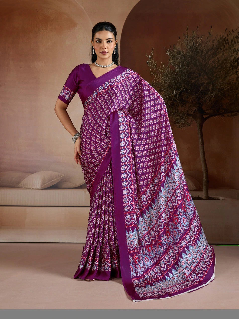 Woman wearing a purple saree with a patterned design in an indoor setting.