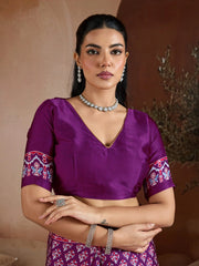 Woman wearing a purple blouse with floral sleeves and a matching skirt against a neutral background