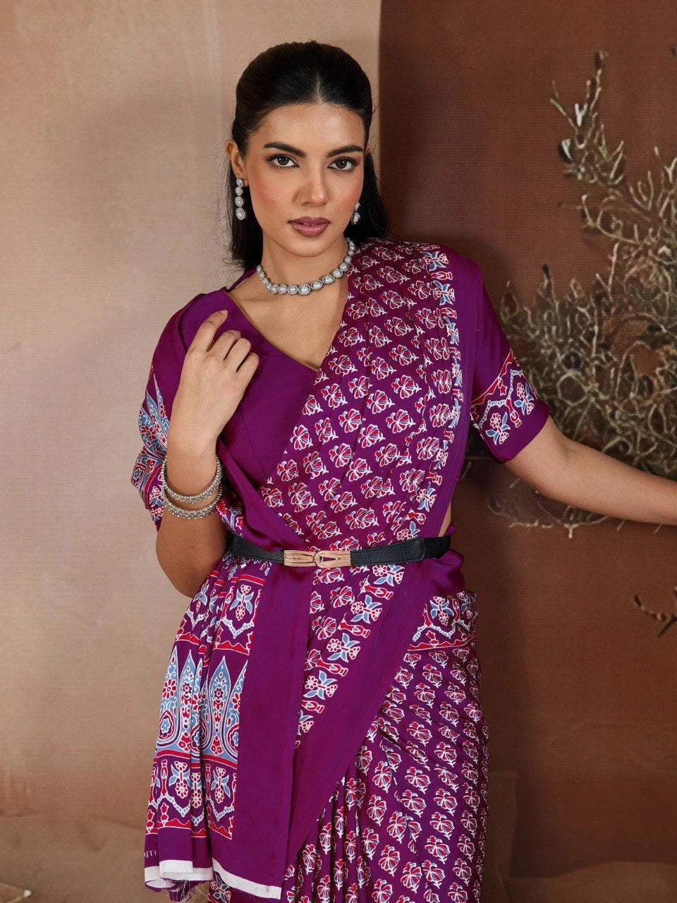 Woman wearing a purple patterned outfit against a brown background