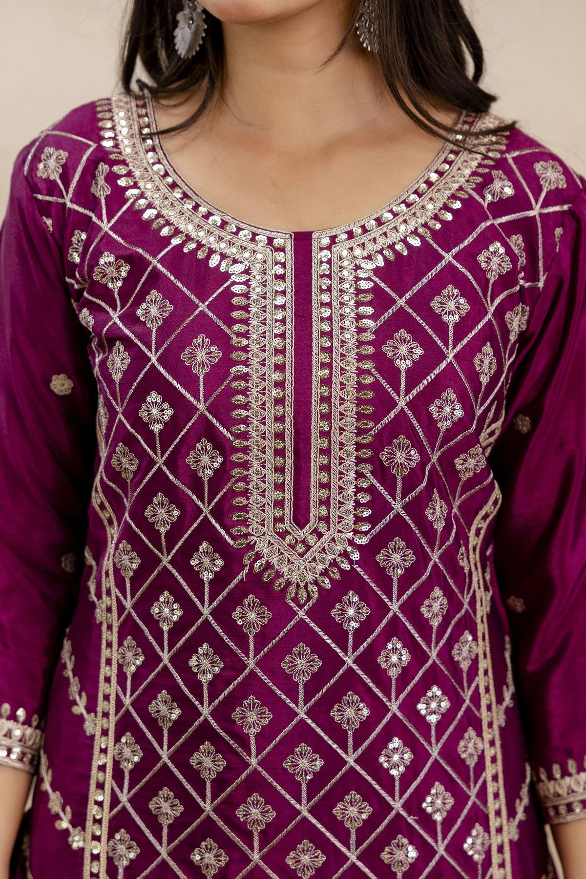 Purple embroidered dress with intricate patterns on a neutral background