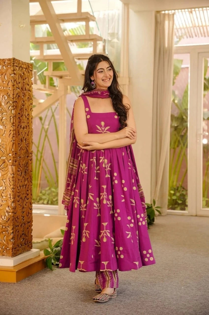 Woman in a purple traditional outfit standing indoors with decorative elements.