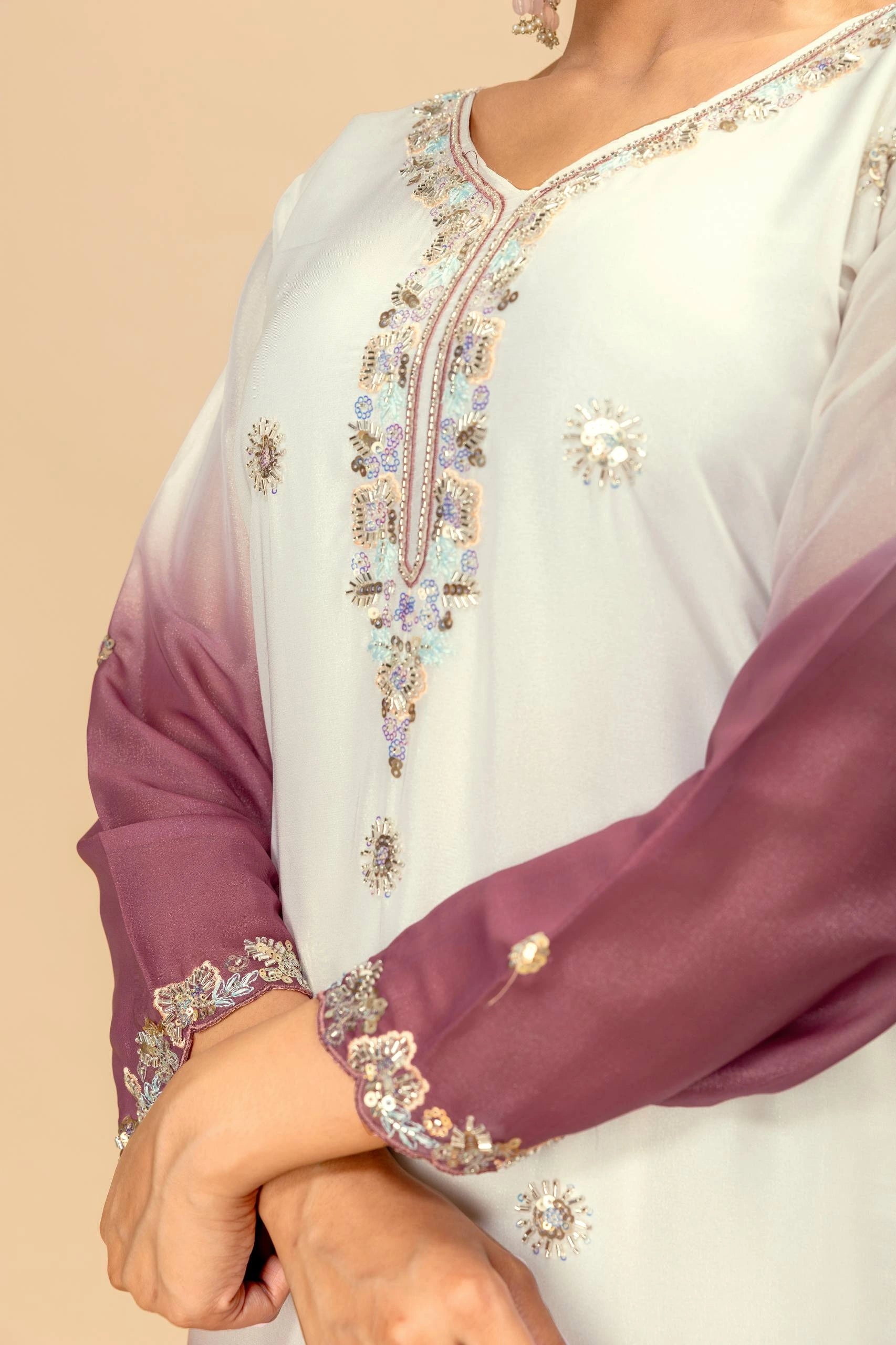 Close-up of a traditional outfit with intricate embroidery on a beige background