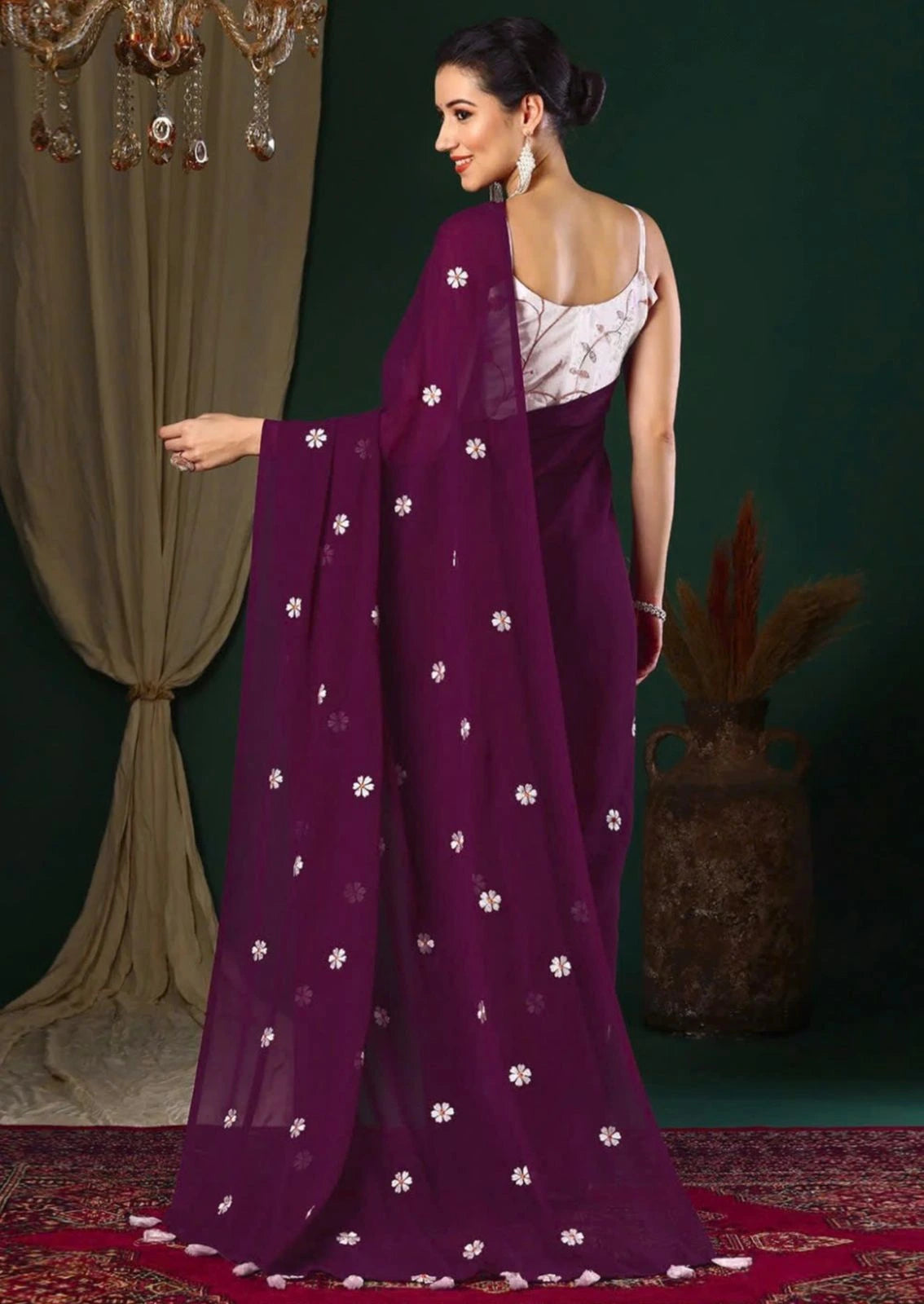 Woman wearing a purple saree with white patterns in a decorated indoor setting
