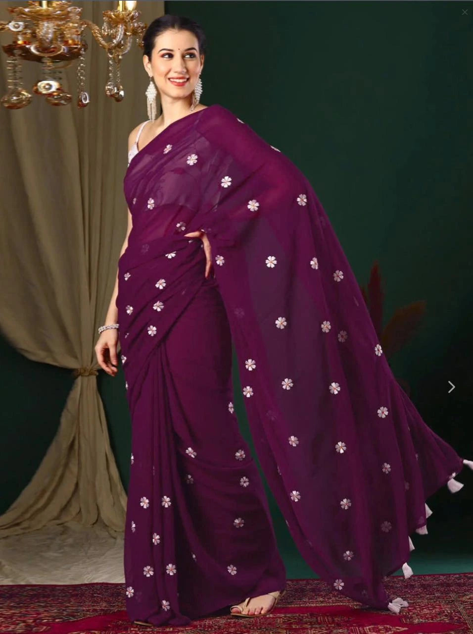 Woman wearing a purple saree with white floral patterns on a dark background