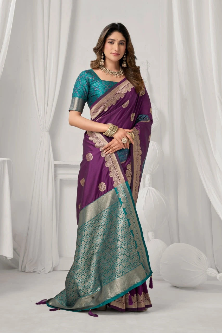 Woman wearing a purple and green saree with a white curtain background