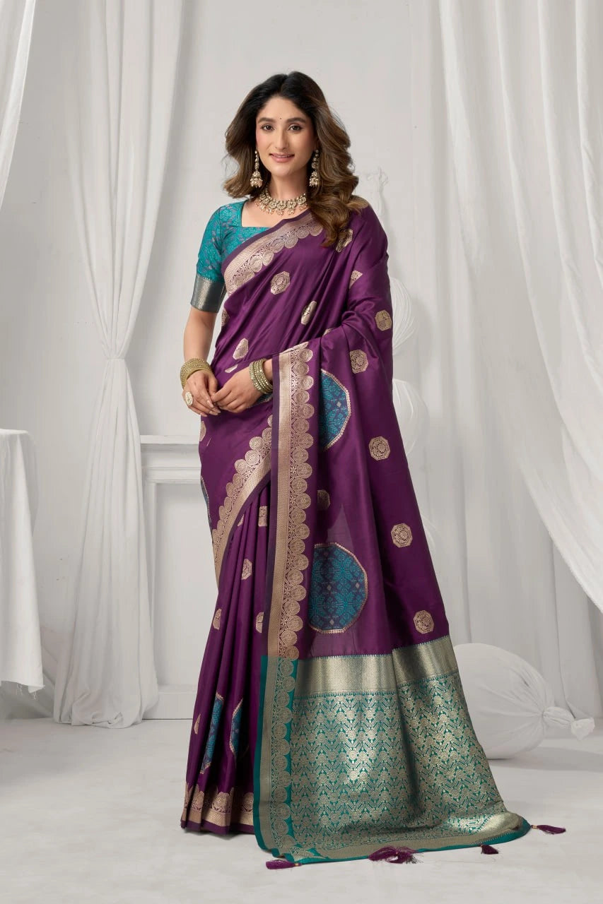 Woman wearing a purple saree with gold and green patterns against a white curtain background