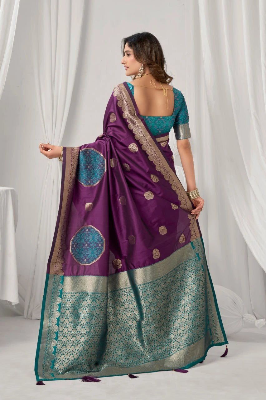 Woman wearing a purple and teal saree with a white curtain background