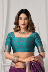 Woman wearing a teal blouse with silver sleeves and a purple saree against a white background