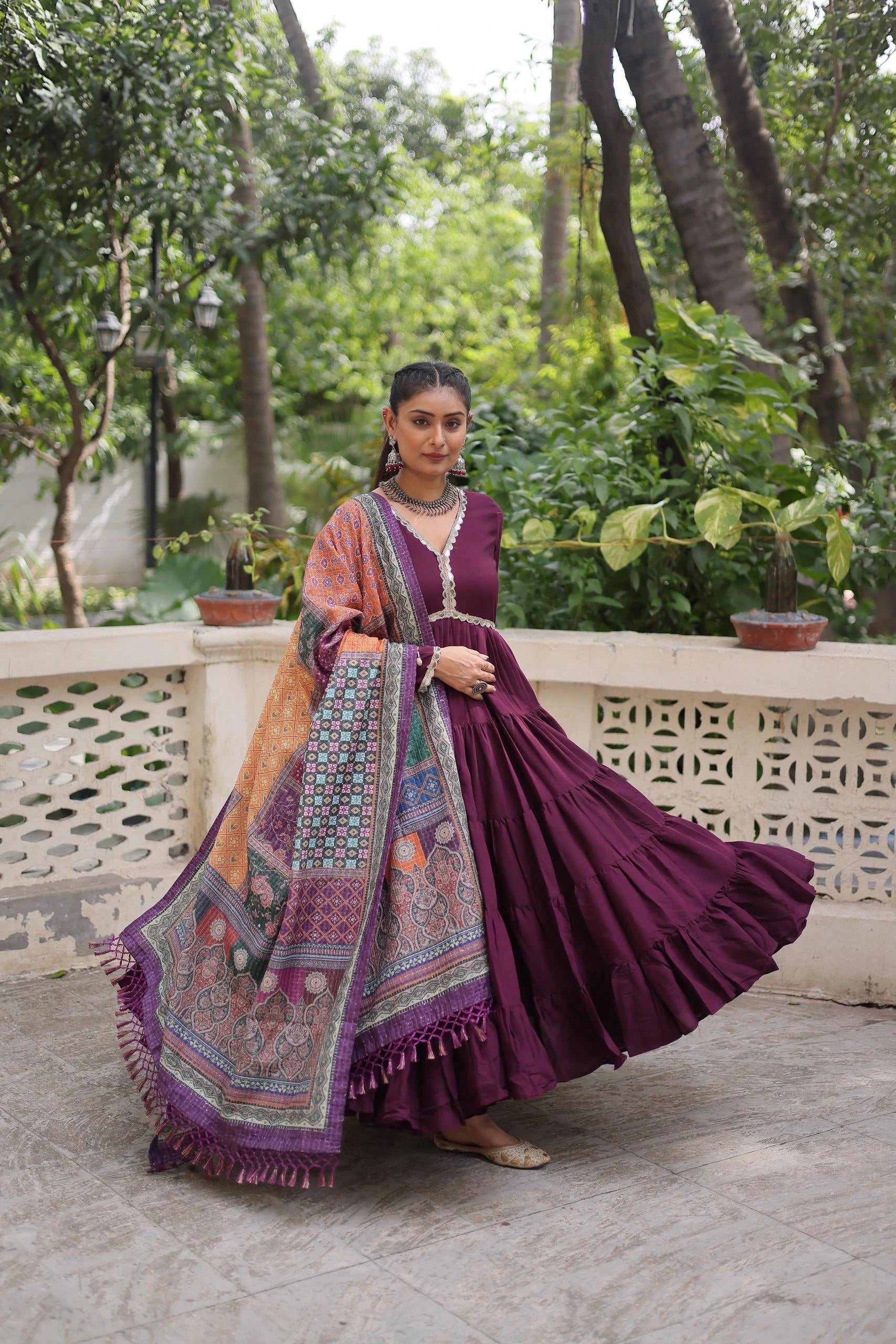 Woman in a traditional outfit with a colorful dupatta standing outdoors.