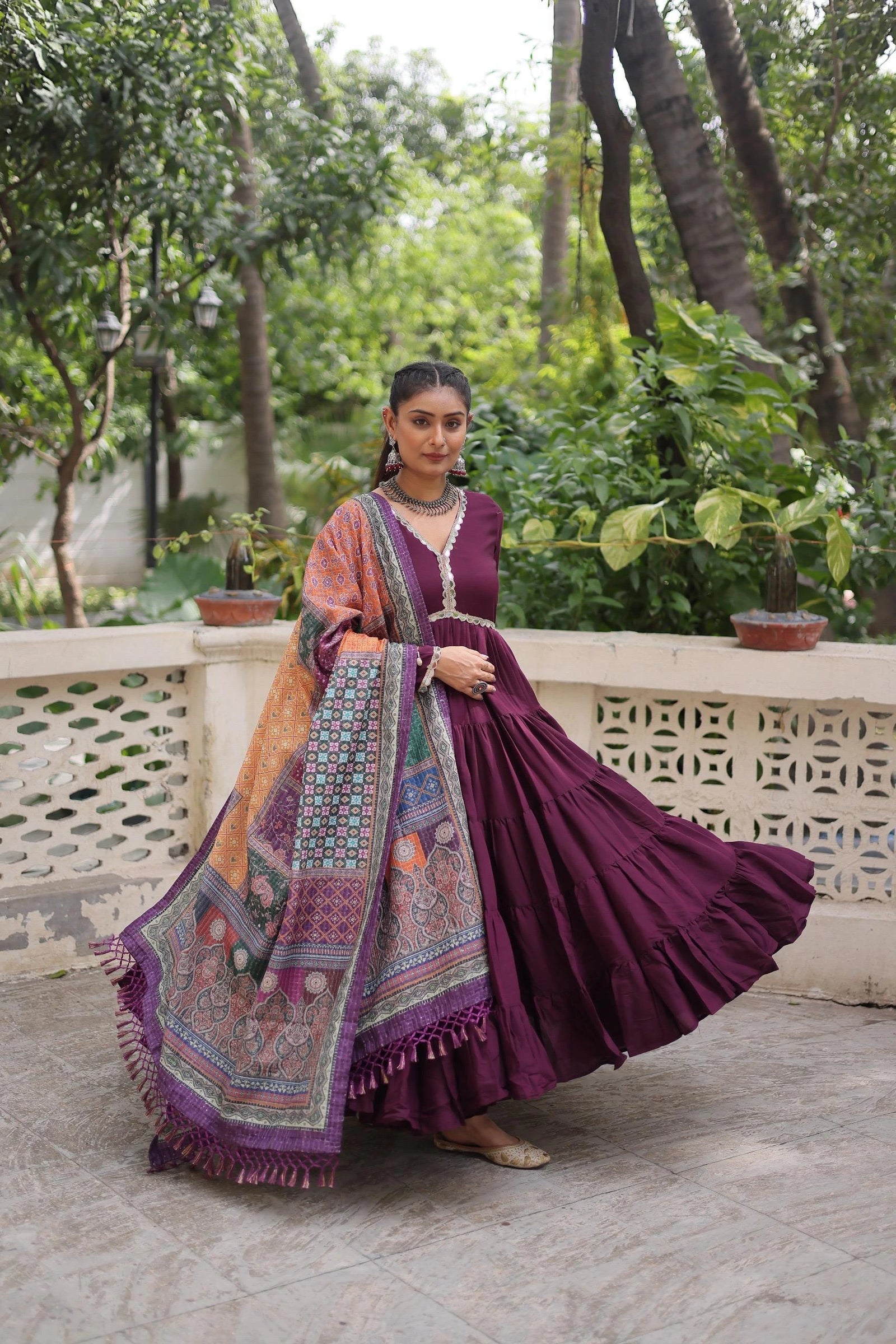 Woman in a traditional outfit with a colorful dupatta standing outdoors.