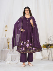 Woman wearing a purple embroidered outfit with a matching dupatta in a white room.