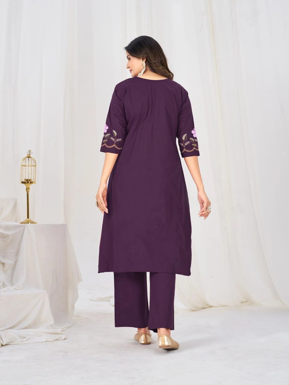 Woman wearing a purple outfit with floral embroidery in a minimalistic setting