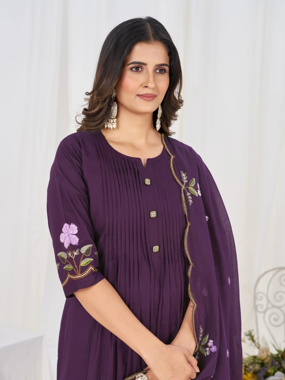 Woman wearing a purple dress with floral embroidery against a white background