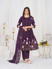 Woman wearing a purple embroidered outfit in a decorated room.