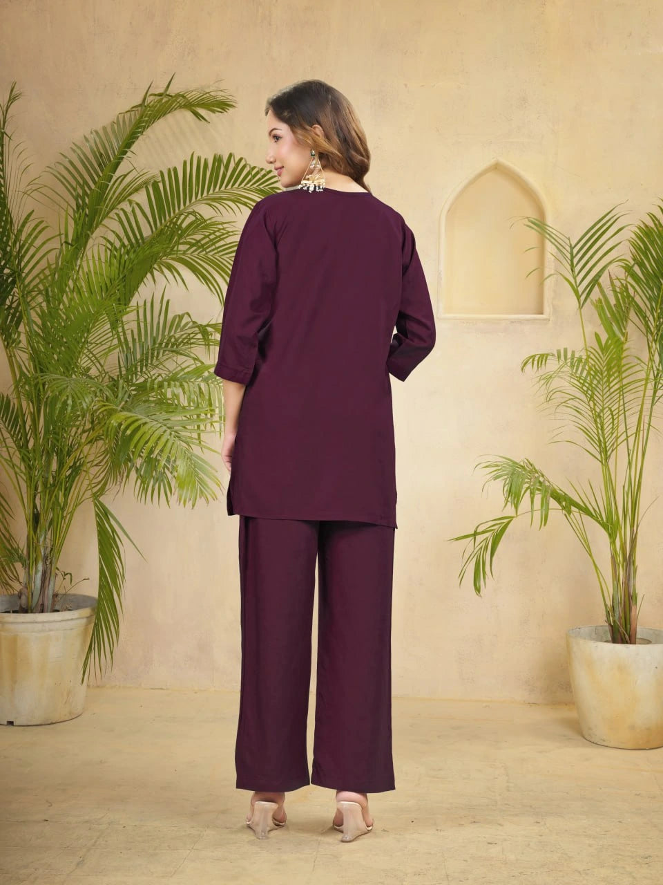 Woman in a purple outfit standing in a room with plants