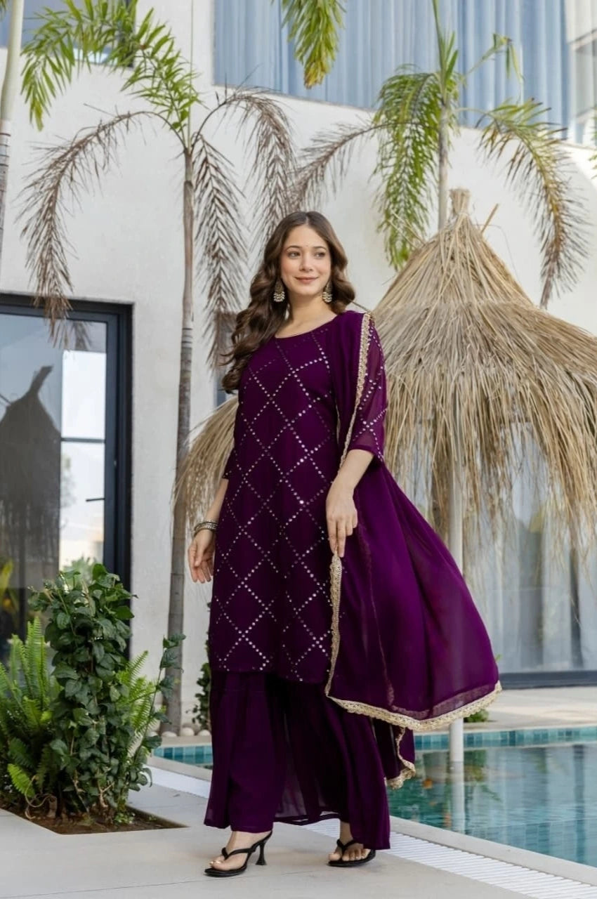 Woman in a purple traditional outfit standing by a pool with palm trees in the background