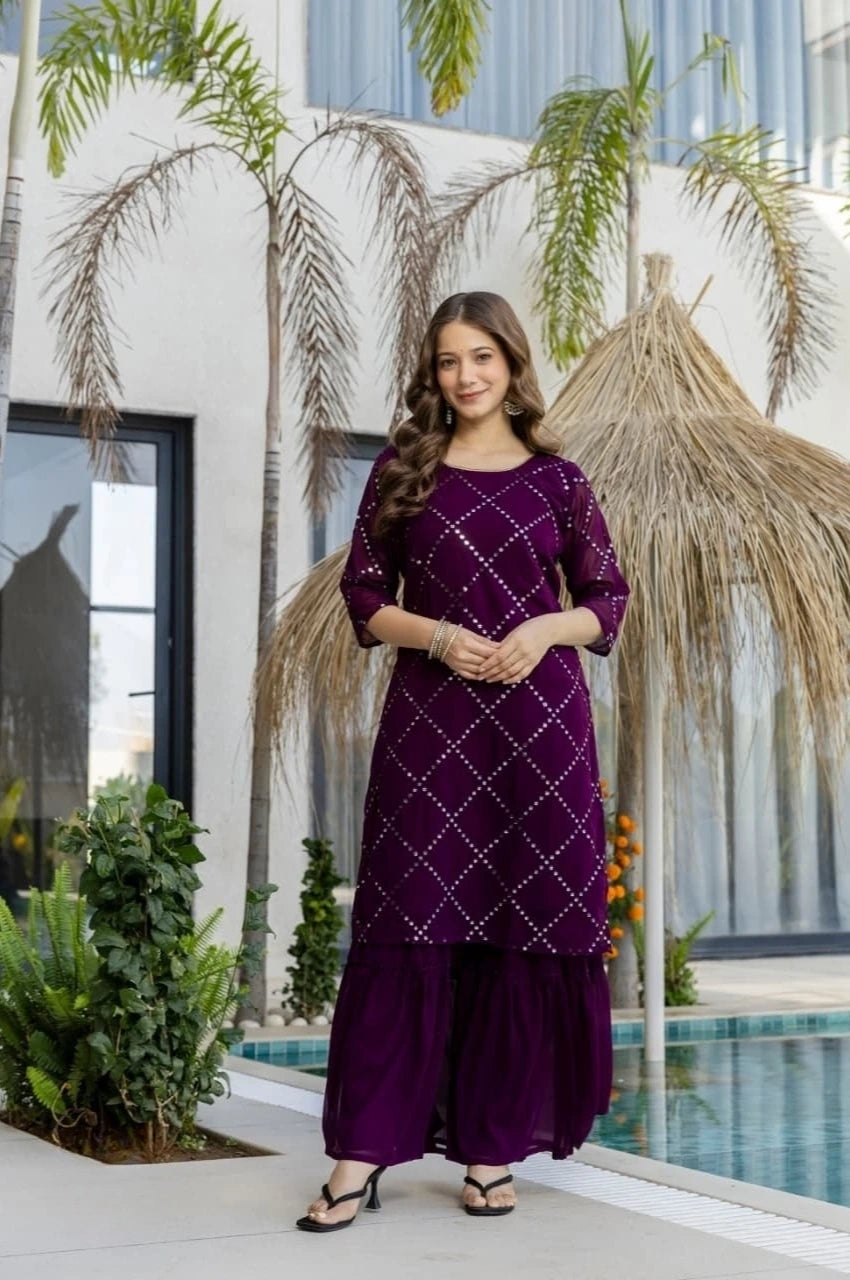 Woman in a purple traditional outfit standing outdoors with plants and a pool in the background