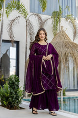 Woman in a purple traditional outfit standing by a pool with palm trees in the background