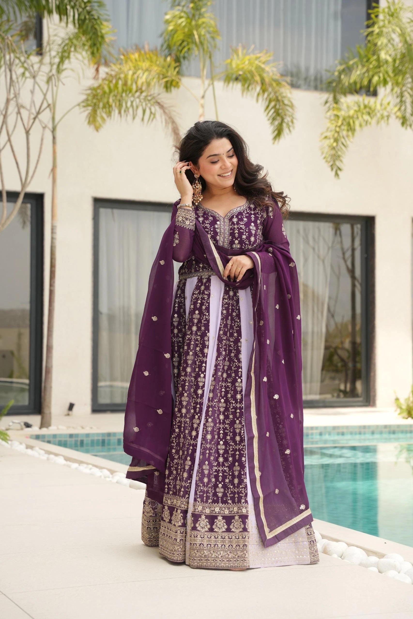 Woman in a purple traditional outfit standing by a poolside.