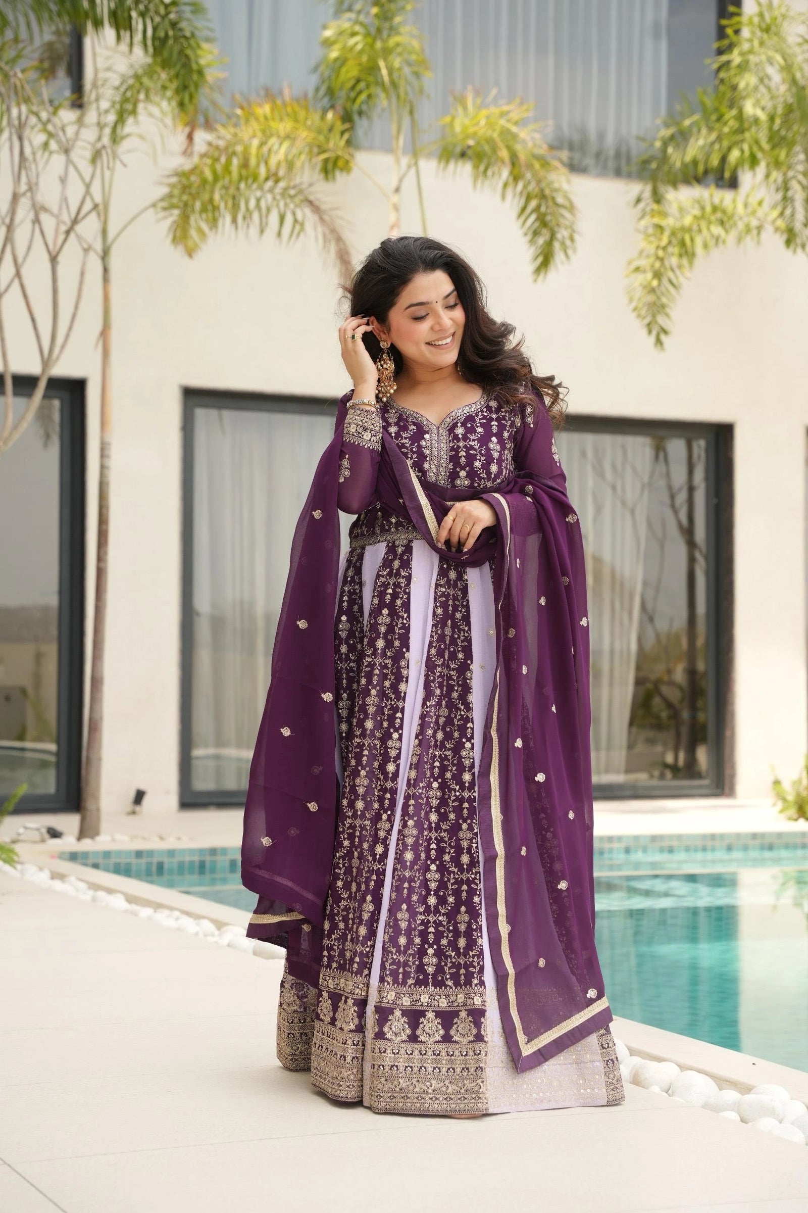 Woman in a purple traditional outfit standing by a poolside.