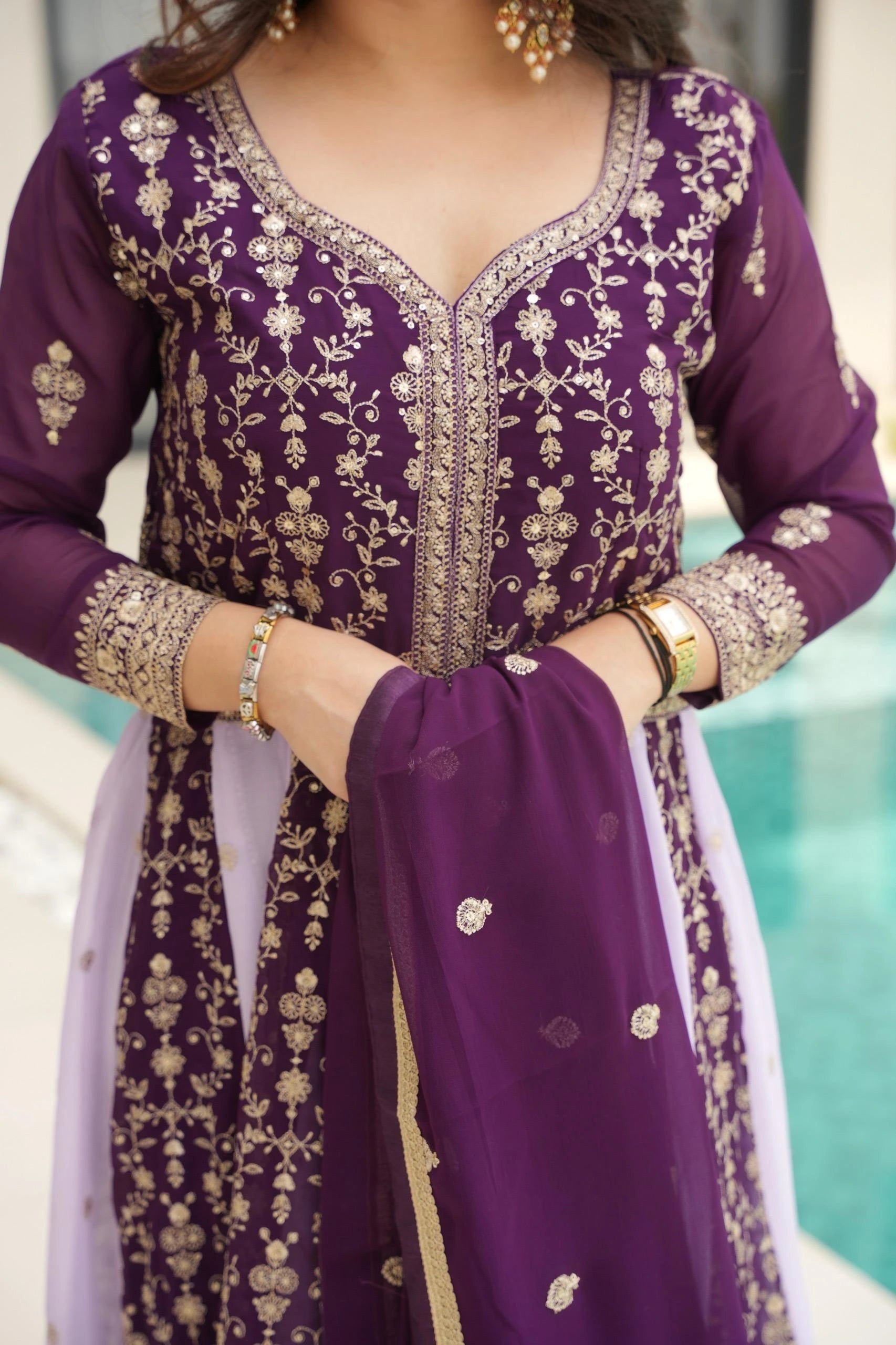 Purple embroidered traditional outfit with gold details on a blurred background
