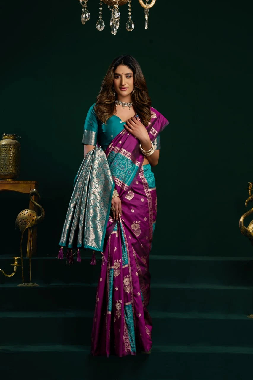 Woman in a purple and blue saree standing on a dark staircase.