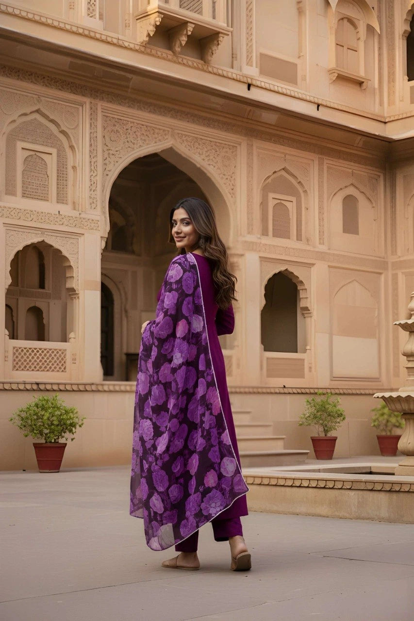 Woman in a purple traditional outfit standing in front of an architectural building with arches.