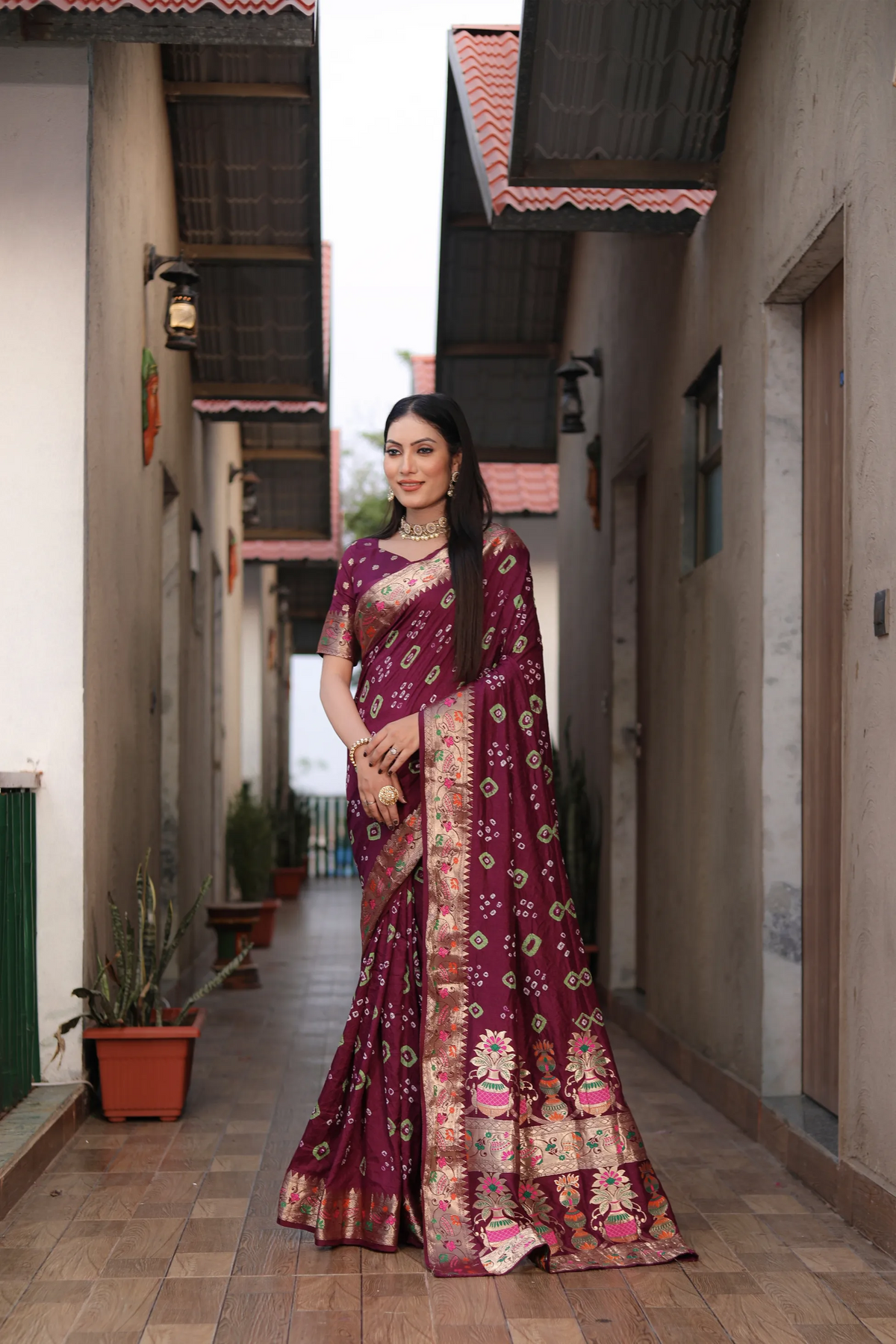 Woman in a traditional saree standing in an alleyway.