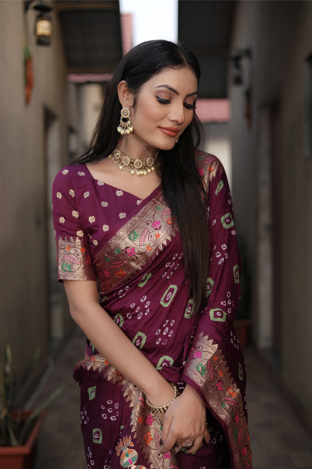 Woman wearing a purple saree with intricate patterns in an outdoor setting