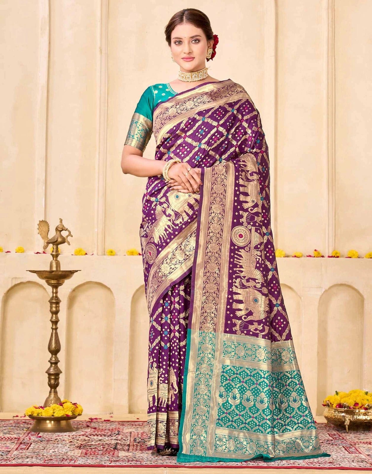 Woman wearing a traditional purple and teal saree in an elegant indoor setting.